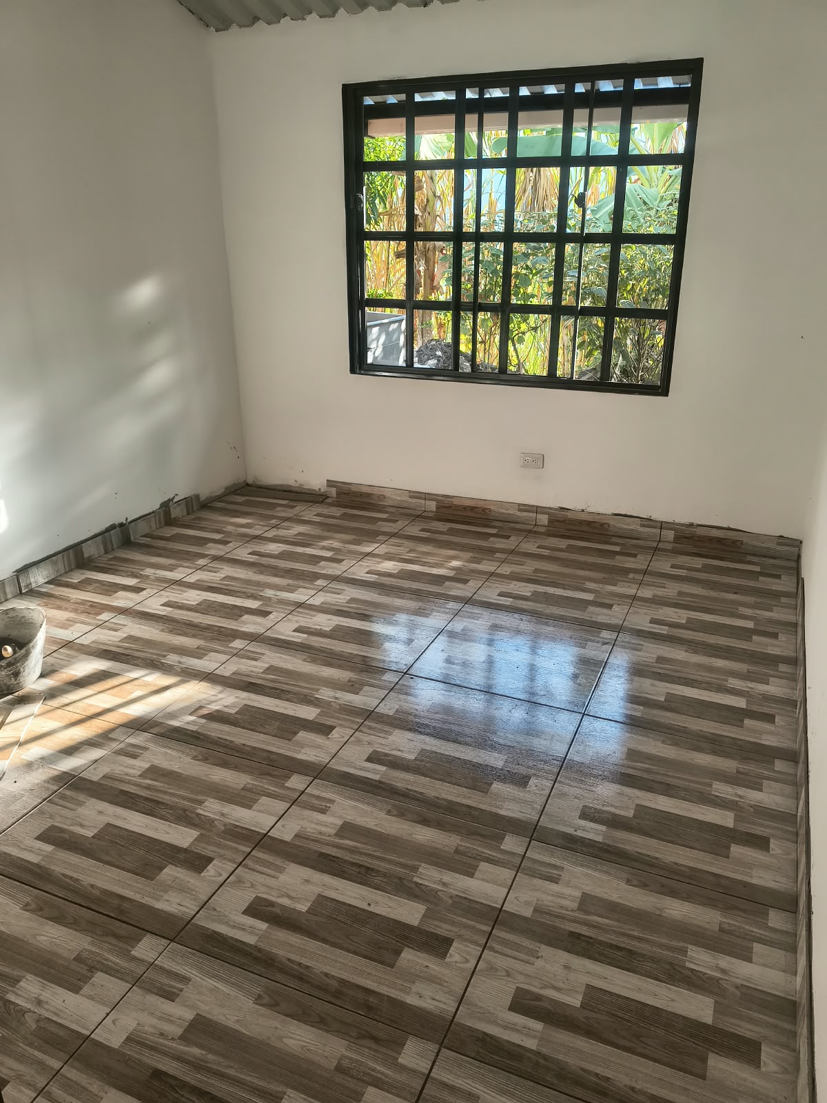 Habitación con ventana y piso de acabado tipo madera